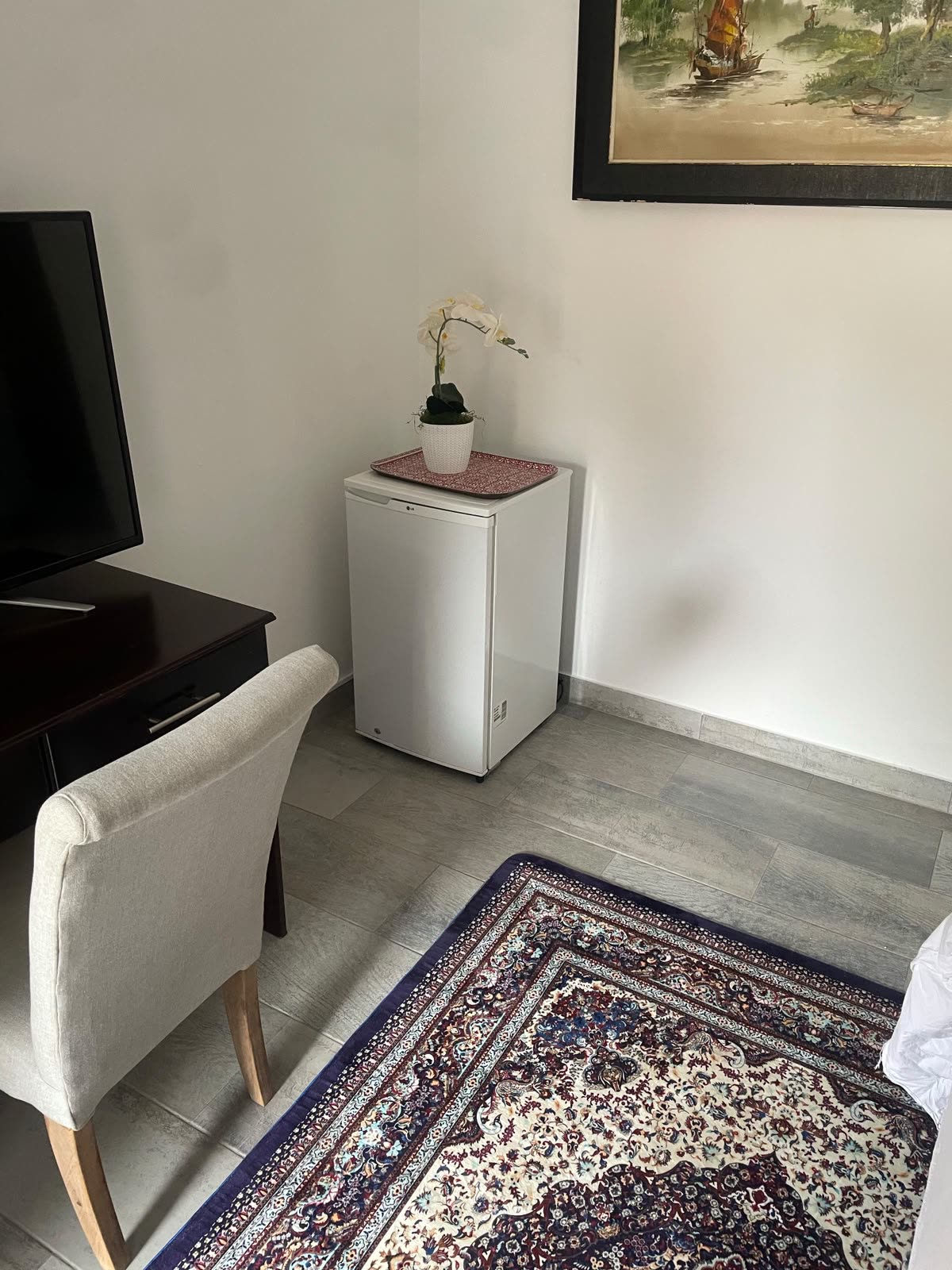 Small fridge unit installed and running in a bright, furnished room